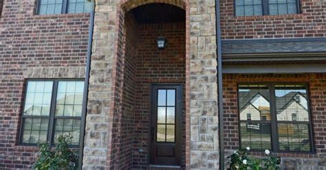 Brick And Stone Exterior Featuring Stone Archway Dark Bronze Windows