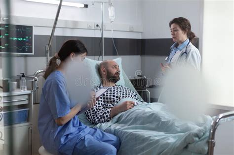 Medical Doctor Explaining Treatment Schedule To Recovering Man While