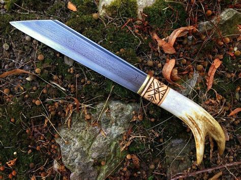 A Knife That Is Laying On The Ground Next To Some Leaves And Grass With