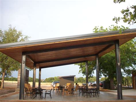 A Covered Patio With Tables And Chairs Under A Shade Structure In The