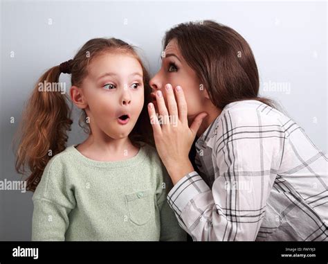 Shocked Mother Whispering The Secret Information To Her Surprising Cute Girl In Ear On Blue