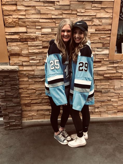 Two Babe Women Standing Next To Each Other In Front Of A Stone Wall Wearing Hockey Jerseys