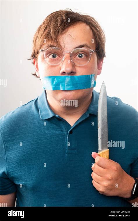 A Man With Glasses Holding Knife With Duct Tape Over Mouth Stock Photo