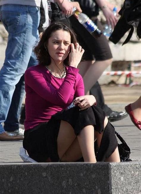 Симпатичная женщина сидя на улице в телесных колготках под юбкой 1
