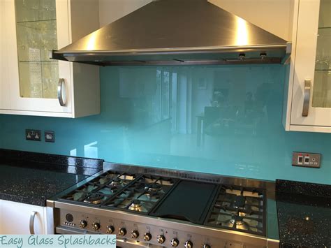 Turquoise Coloured Glass Splashback In A White Kitchen With Black Worktops Visit