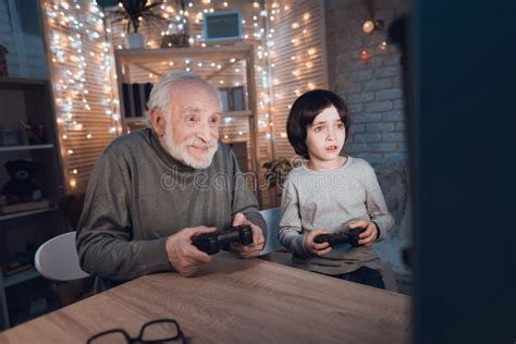 Grandfather And Grandson Are Playing Video Games On Computer At Night
