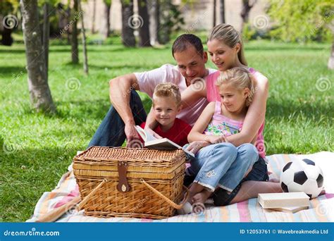 Padres Y Sus Niños Que Leen En El Parque Imagen De Archivo Imagen