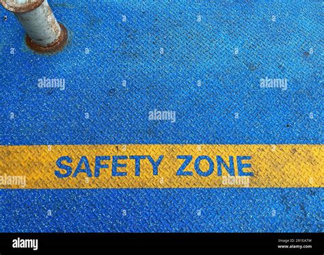 The Yellow Safety Zone Text Mark On Steel Floor With Blue Grunge Tarmac