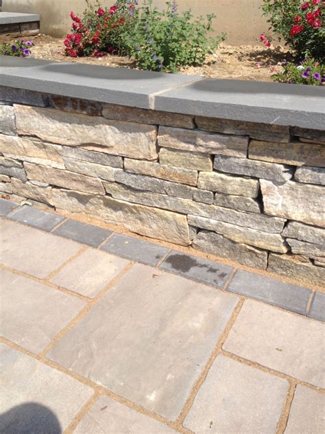 Close Up Of A Natural Stone Retaining Wall With Bluestone Cap And Paver