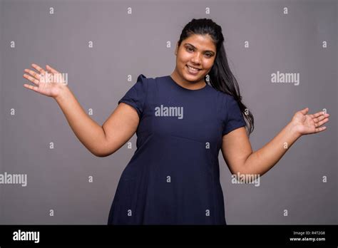 Young Overweight Beautiful Indian Woman Against Gray Background Stock