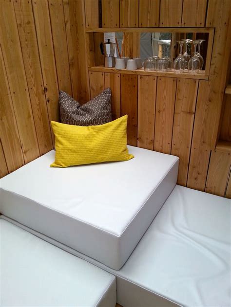 A White Bed Sitting Next To A Wooden Wall With Two Pillows On Top Of It