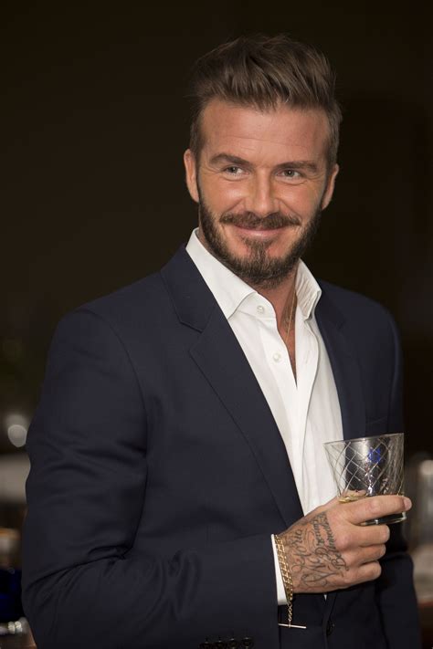 A Man With A Beard Holding A Glass In His Hand And Smiling At The Camera