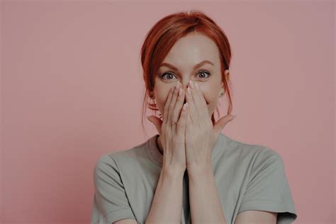 Young Pretty Ginger Woman Covering Mouth With Both Hands Being In