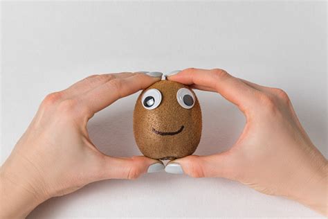 Hands Holding Fruit Kiwi With Funny Face And Googly Eyes