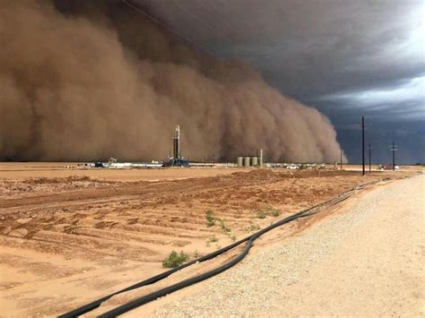 A Large Dust Cloud Is In The Sky Over A Dirt Road