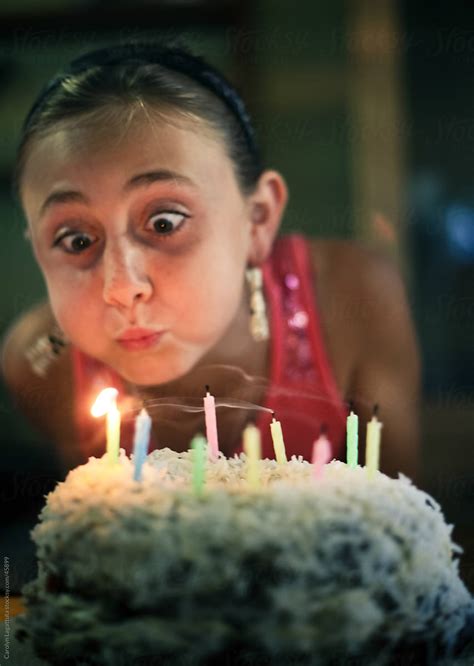 Girl With Wide Eyes And Puffy Cheeks Blowing Out Birthday Candles On A
