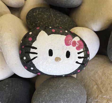 A Hello Kitty Rock Sitting On Top Of Some Black And White Rocks With
