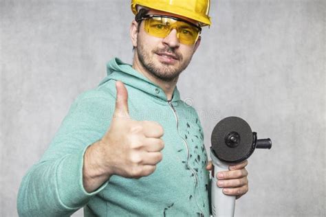 The Construction Worker Holds An Angle Grinder In His Hand Stock Image