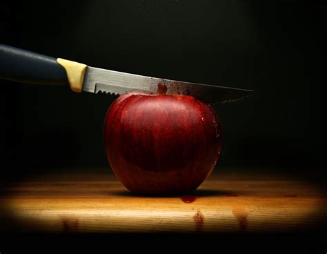 A Knife Cutting A Red Apple And Blood Flowing On Dark Background
