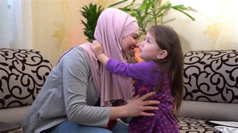 Happy Muslim Mother And Little Daughter Loving Mother In Hijab Hugs And Kisses His Smiling