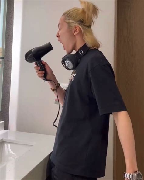 A Woman Blow Drying Her Hair In Front Of A Mirror While Holding A Hair