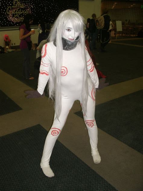 A Person In A White Body Suit With Long Hair And Grey Wig Standing On