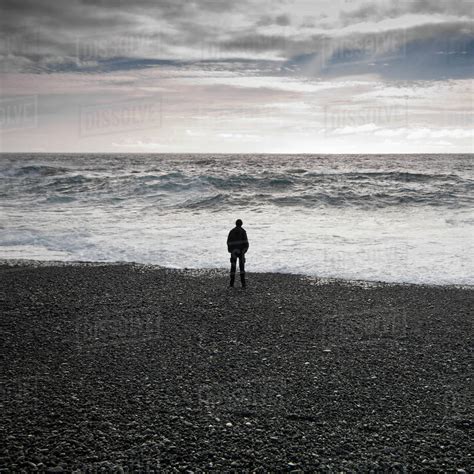 Man Standing On Black Beach Looking Out To Sea Djupalonssandur