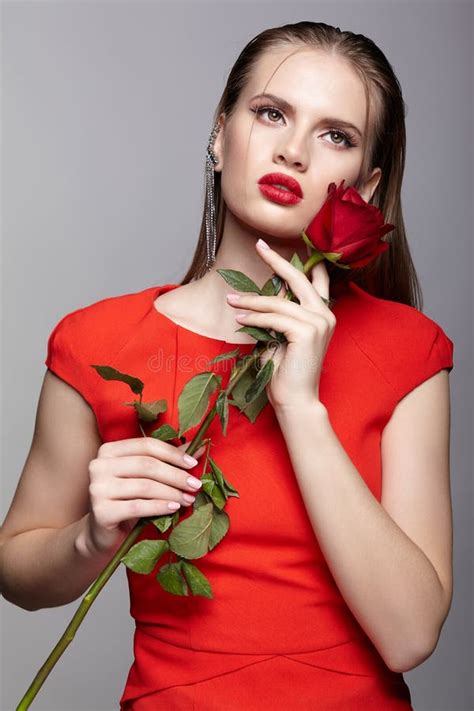 Portrait Of Young Woman In Red Dress And Red Rose In Hand Stock Image