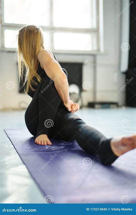 sporty flexible blonde woman in black sportswear practicing yoga in yoga class making