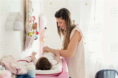 Mother Changing Baby Girls Diaper On Changing Table Stock Photo