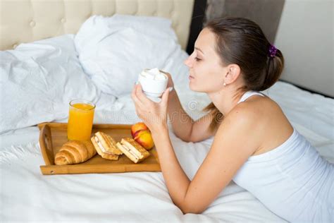 beautiful brunette girl eating a healthy breakfast and drinking coffee in bed stock image