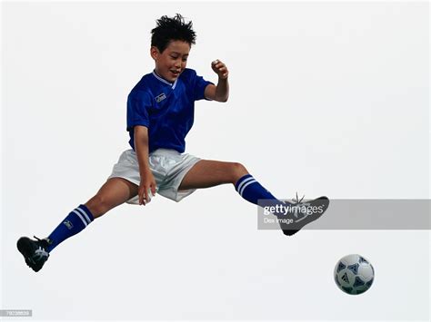 Young Asian Boy Kicking Football In Mid Air High-Res Stock Photo ...