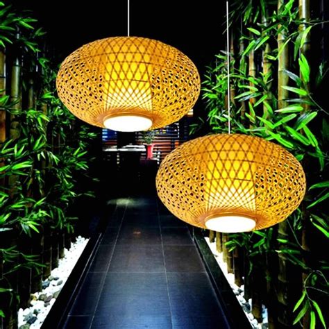 Two Lamps Hanging From The Ceiling In Front Of Bamboo Trees
