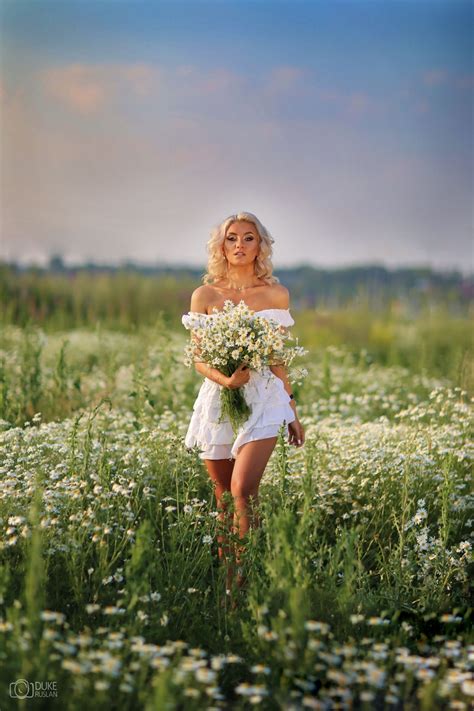 Фото Девушка блондинка с букетом ромашек на цветущем поляне Фотограф