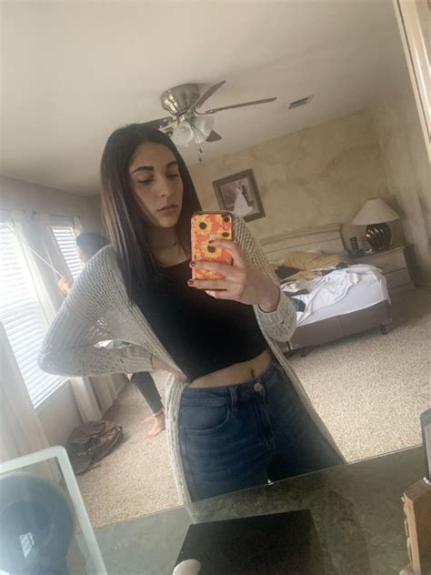 a woman is taking a selfie in the mirror while wearing jeans and a crop top