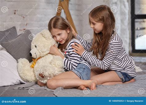 Das Bild Von Zwei Kleinen Schwestern Die Auf Dem Bett Im Zimmer Sitzen Stockbild Bild Von