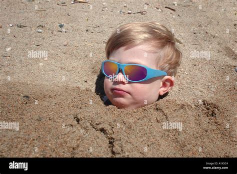 Small Boy Buried In Sand Up To His Head Smiling With Sunglasses On