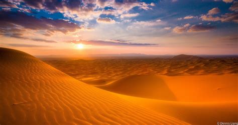 The Sun Is Setting Over Sand Dunes In The Desert