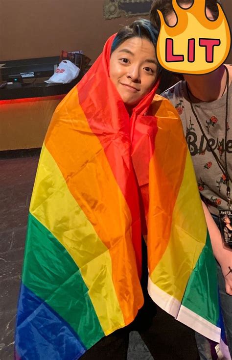 Two People Standing Next To Each Other With A Rainbow Colored Cape On