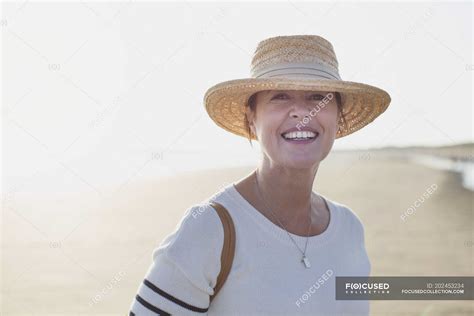 Portrait Smiling Mature Woman Wearing Straw Hat On Sunny Summer Beach — Retirement Sun Hat