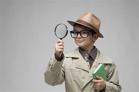 Little Detective Looking Through Magnifying Glass On Gray Background