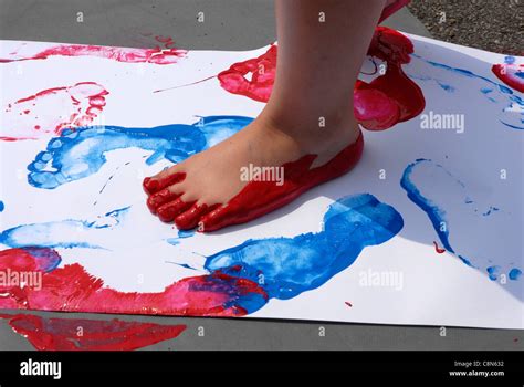 Nursery Child Painting Footprints By Walking In Paint With Bare Feet