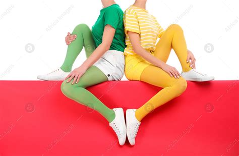 Women Wearing Bright Tights Sitting Together On Color Background