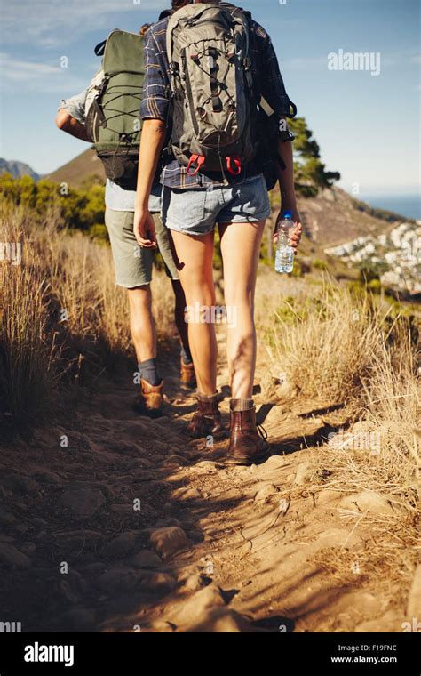 Rear View Of Young Couple Trekking Together In Countryside Hiker