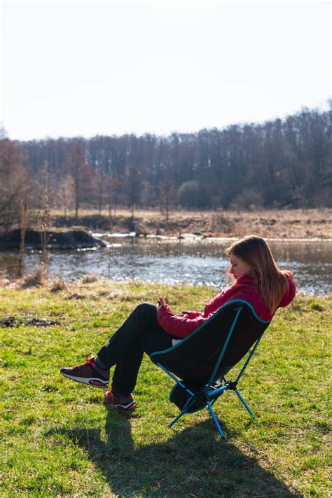 Outdoor Portrait Of Woman Sitting In Folding Chair With Smartphone Near