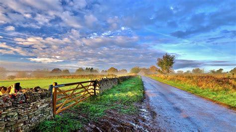 Sunrise Over The Country Side Road And Fence