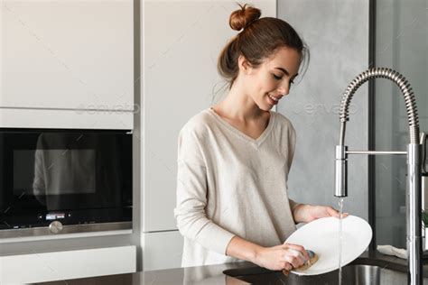 Portrait Of A Smiling Young Woman Washing Dishes Stock Photo By