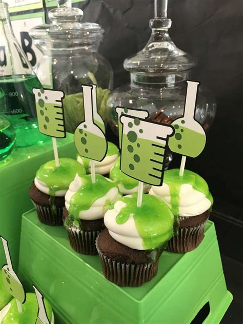 Some Cupcakes With Green Frosting And Lab Equipment On Them Are Sitting