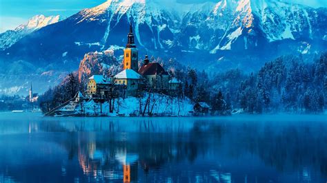 Castle In Middle Of Lake Around Snow Covered Mountains And Trees Under