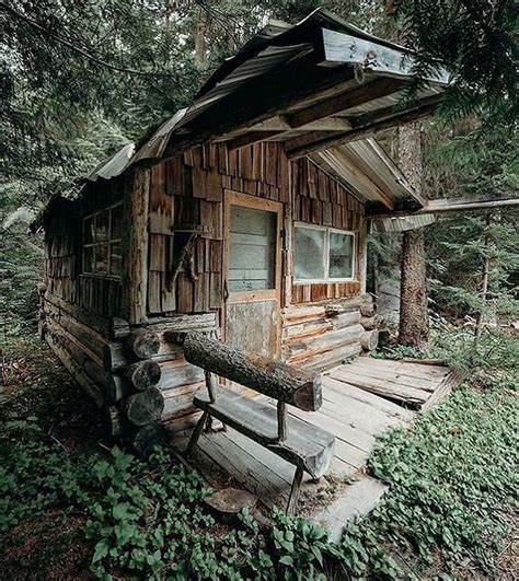 An Old Log Cabin In The Woods With A Wooden Bench And Window On The Front